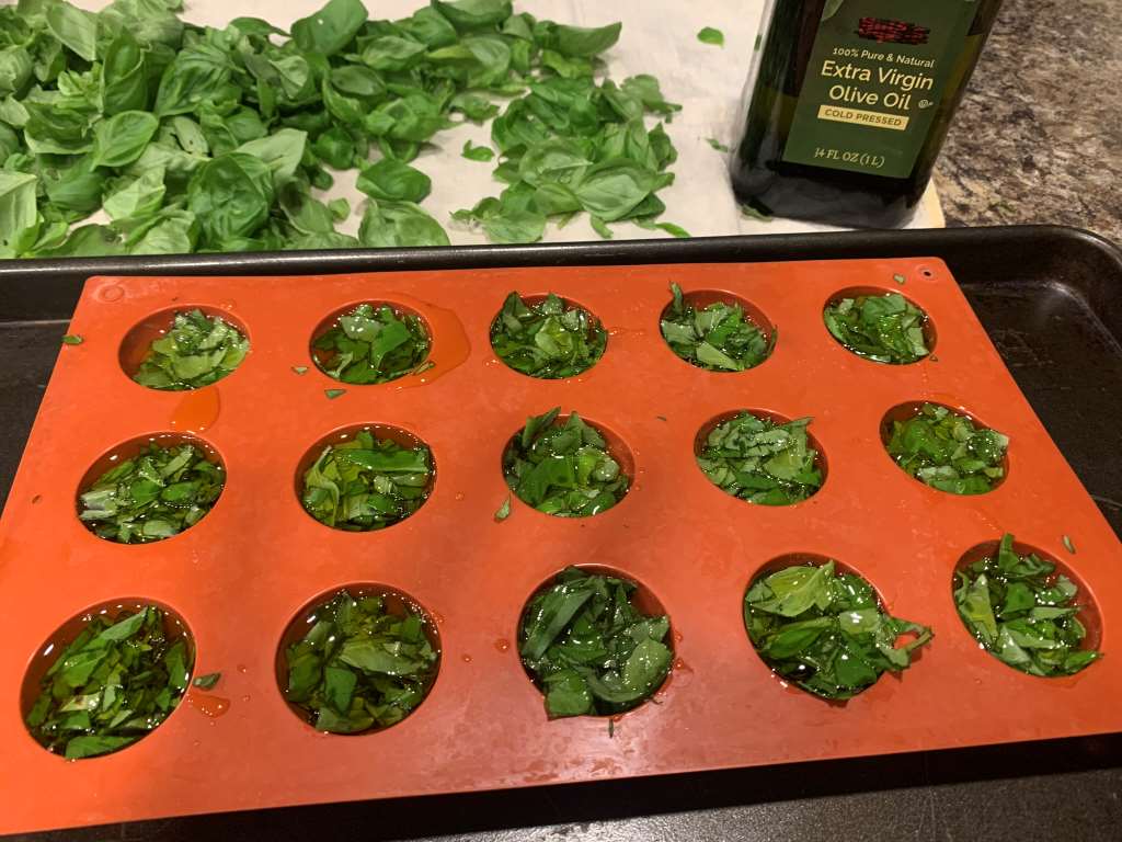 chopped basil in orange ice cube tray